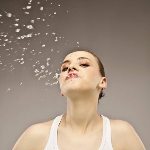 Frau spuckt Flüssigkeit aus