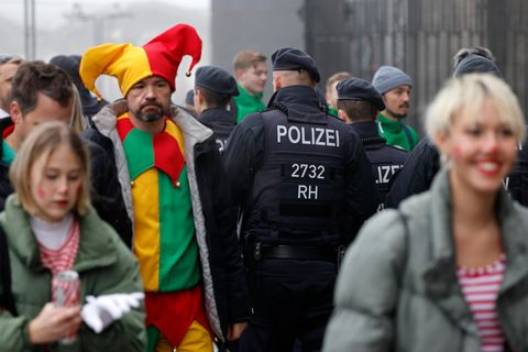 Verkleidete Menschen an Karneval gehen an Polizisten vorbei