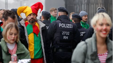 Verkleidete Menschen an Karneval gehen an Polizisten vorbei