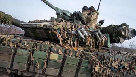 Ein Panzer, auf dem zwei Soldaten sitzen und der mit einem Tarnnetz ausgestattet ist, fährt durch Siversk