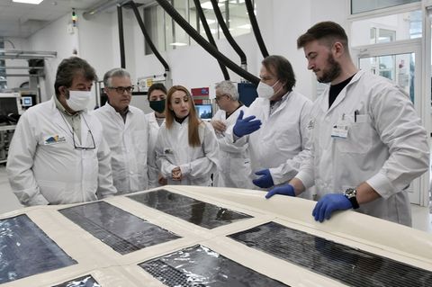 Ein Forschungsteam ist um Solarpanels versammelt. Es möchte Photovoltaik in Masse produzieren.
