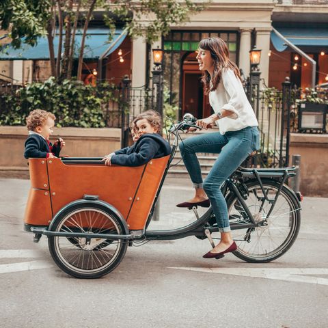 Eine Frau fährt mit drei Kindern in einem Lastenrad durch die Stadt