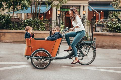 Eine Frau fährt mit drei Kindern in einem Lastenrad durch die Stadt