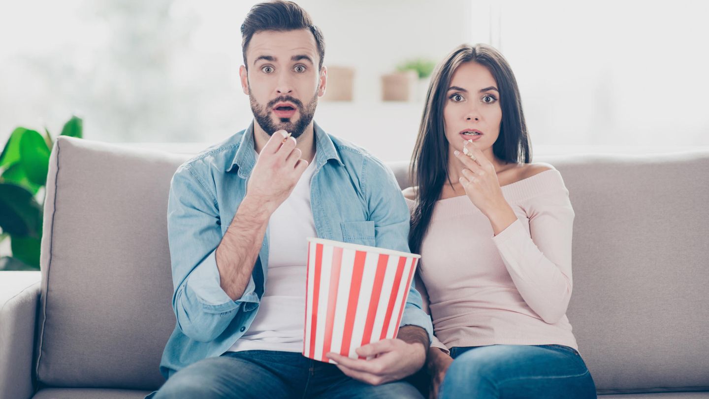 Paar schaut geschockt Richtung Fernseher