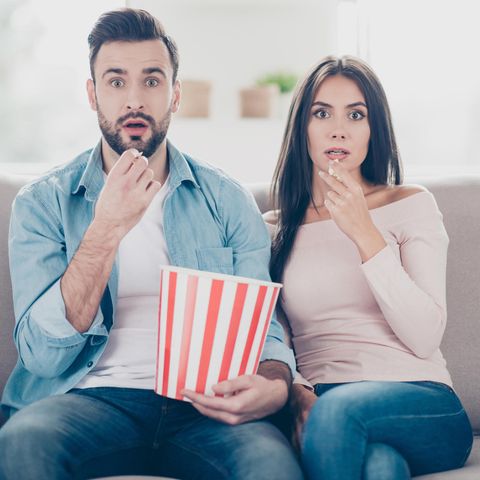 Paar schaut geschockt Richtung Fernseher