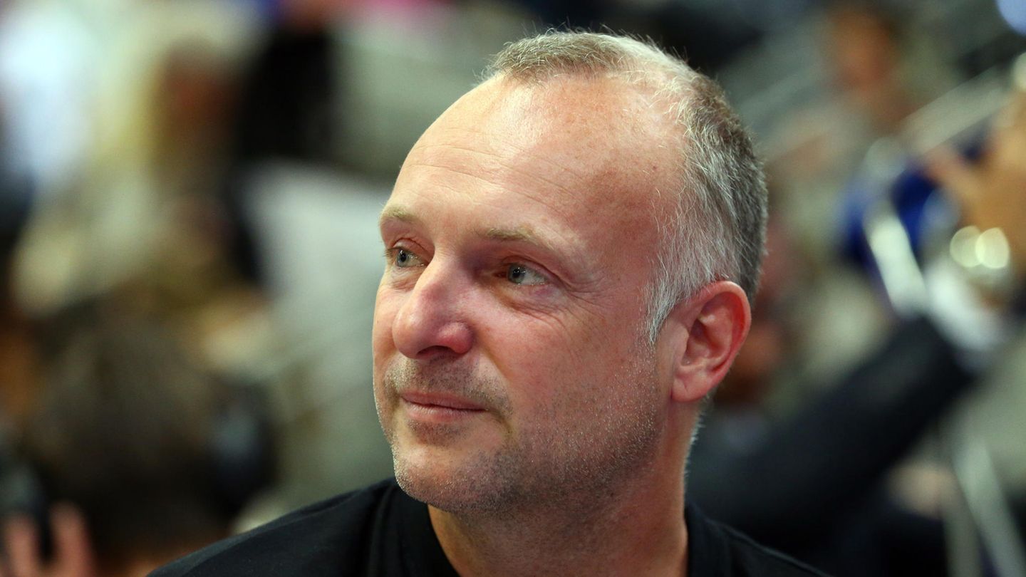 Frank Buschmann, ein weißer Mann mit grau-blondem Kurzhaarschnitt, hat seinen Kopf nach rechts gedreht und lächelt leicht