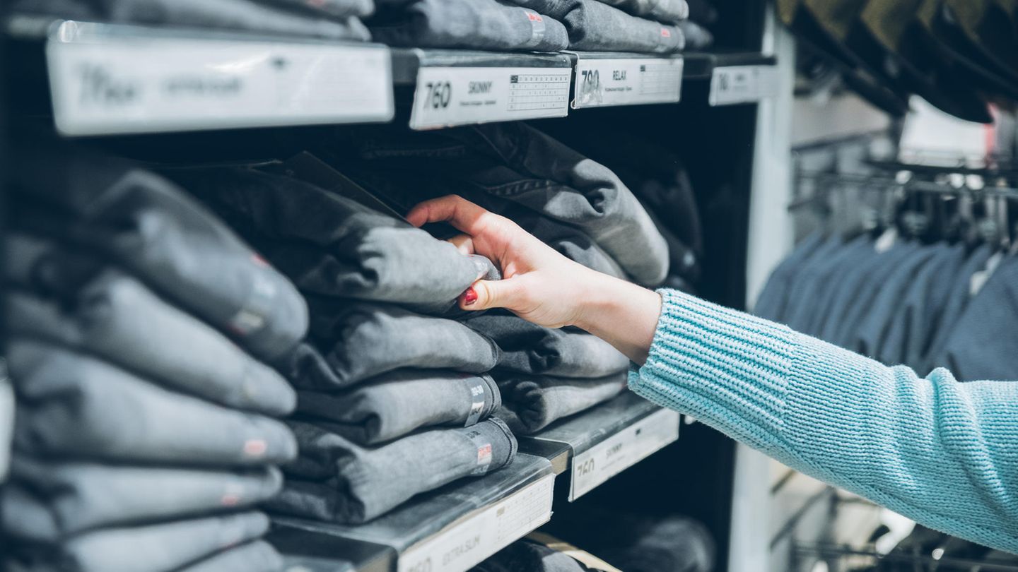 Kundin greift im Laden zu einer Jeans im Regal