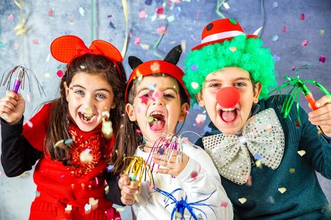 Kinder gucken am Kinderfasching verkleidet in die Kamera