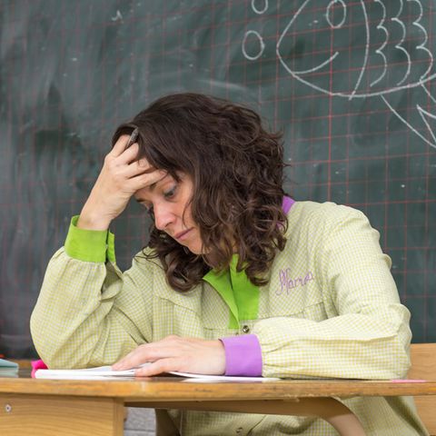 Müde Lehrerin sitzt am Pult
