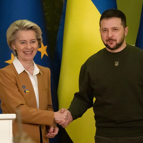 Ursula von der Leyen und Wolodymyr Selenskyj geben einander vor Flaggen der EU und der Ukraine die Hand