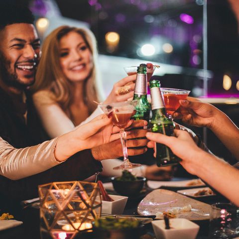 Eine Gruppe sitzt am Tisch beisammen und trinkt Alkohol