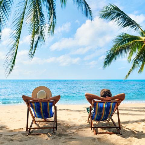 Zwei Männer sitzen entspannt am Strand auf Liegestühlen