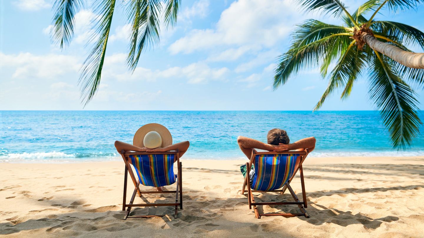 Zwei Männer sitzen entspannt am Strand auf Liegestühlen Zwei Männer sitzen entspannt am Strand auf Liegestühlen