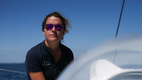 Clarisse Crémer sitzt in blauem Polo-Shirt und mit verspiegelter Sonnenbrille an Bord einer Segeljacht in der Sonne