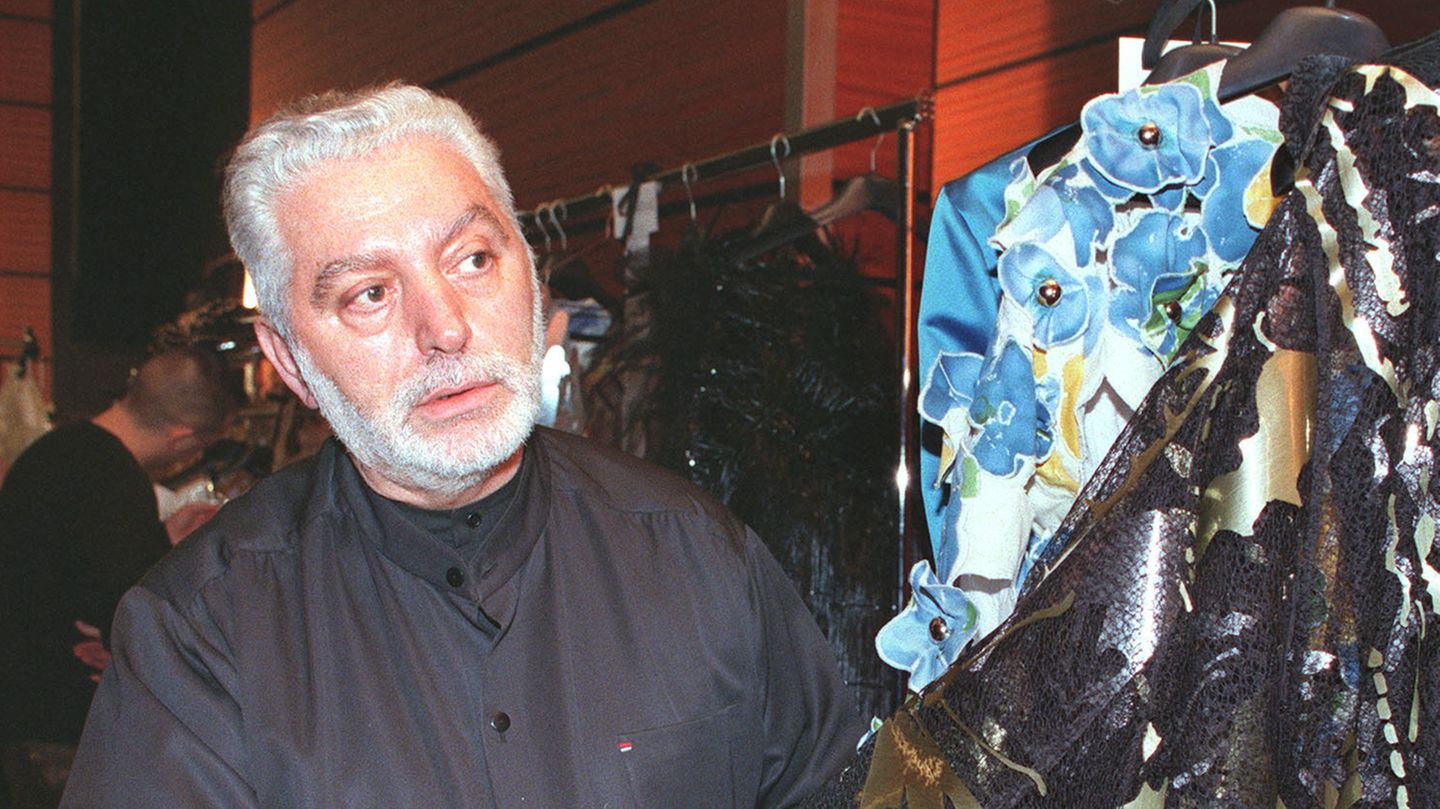 Modedesigner Paco Rabanne steht neben einem Kleiderständer mit einigen seiner Kreationen
