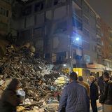 Menschen versammeln sich in Pazarcik. Vor ihnen sind die Überreste dessen, was einmal ein Gebäude war. 