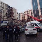 Rettungskräfte und medizinische Teams versuchen verschüttete Bewohner aus einem eingestürzten Gebäude zu retten