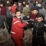 Rettungskräfte und Menschen tragen eine verletzte Person aus den Trümmern eines zerstörten Gebäudes