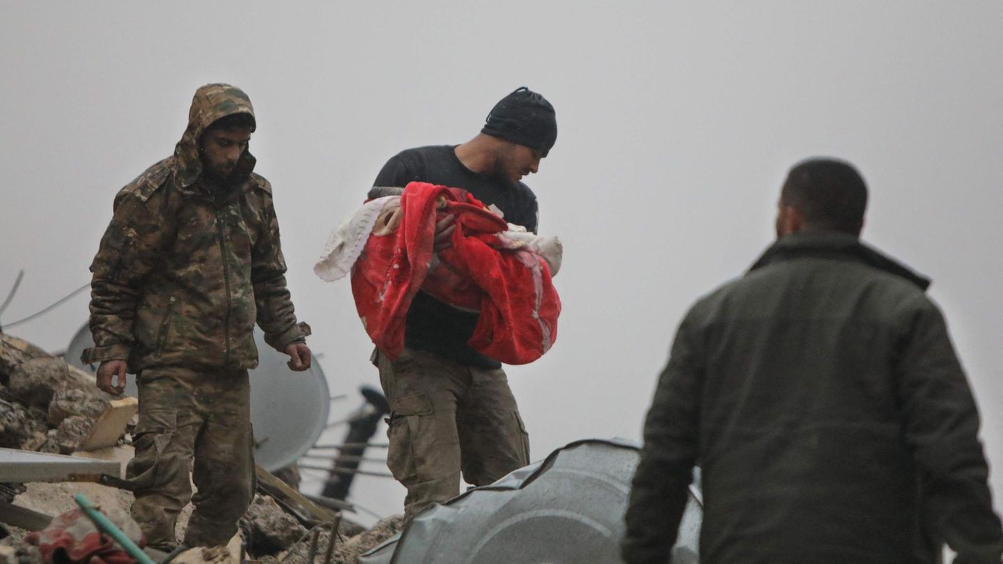 Ein syrischer Mann trägt die Leiche eines Kleinkinds