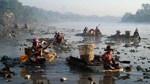 Rangun, Myanmar. Menschen paddeln mit Styroporbooten durch den Pazundaung, um beispielsweise nach Kunststoff und Glas zum Recyceln zu suchen. Dutzende begeben sich in die trüben Gewässer, um Abfall zu sammeln, nachdem sie durch eine Wirtschaftskrise ihre Arbeit verloren haben.