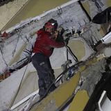 Nach dem Erdbeben in der Türkei steht ein Retter auf einem Trümmerberg und leuchtet mit einer Stirnlampe