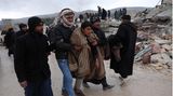 In Besnaya, einem Dorf in Syrien, bringen Männer einen aus den Trümmern geretteten Jugendlichen weg