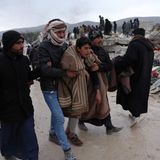 In Besnaya, einem Dorf in Syrien, bringen Männer einen aus den Trümmern geretteten Jugendlichen weg