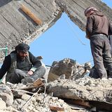 Ein Mann sitzt auf einem Trümmerberg und weint