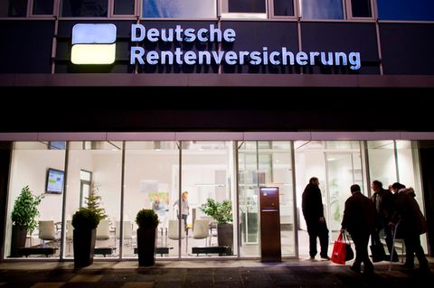 Eine Filiale der Deutschen Rentenversicherung im Dunkeln, davor Menschen