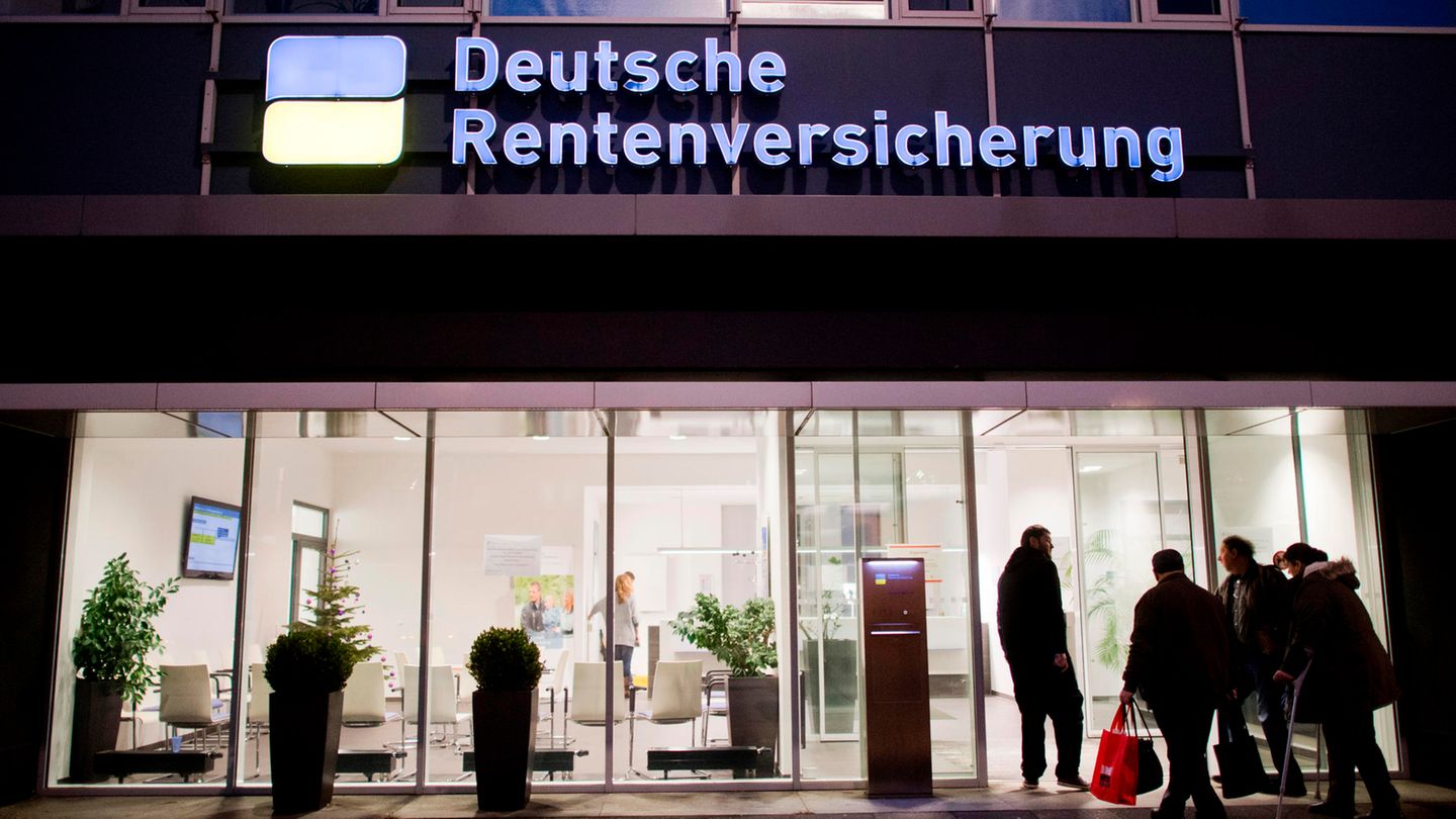 Eine Filiale der Deutschen Rentenversicherung im Dunkeln, davor Menschen