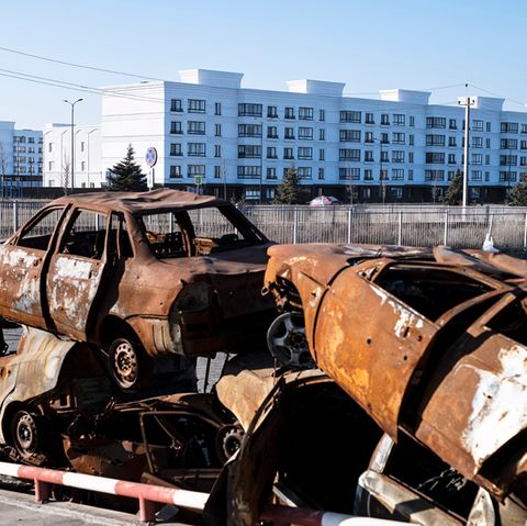 Vor einer Neubausiedlung in Mariupol türmen sich ausgebrannte Autos