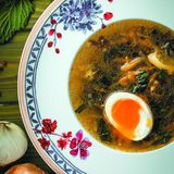 Grüner Borschtsch  Zutaten:  · 2 Hähnchenviertel · 3 l Wasser · 2 Zwiebeln · 1 Karotte · 1/4 Sellerieknolle · 2–3 Lorbeerblätter · 3–4 Pimentkörner · 3–4 mehligkochende Kartoffeln · 1 Bund Sauerampfer · 1 Bund Brennnessel · 3–4 Eier · 3 EL Pflanzenöl · 10 Stängel Petersilie · Salz  1 Stunde 6-8 Personen  Zubereitung:  1. Die Hähnchenviertel gut waschen und mit Küchenpapier trocken tupfen. Mit einer ganzen Zwiebel in einen Topf geben und mit Wasser bedecken. 1/2 Karotte und den Knollensellerie in große Stücke schneiden und mit Lorbeerblättern und Pimentkörnern in den Topf geben. Auf niedriger Stufe 30 Minuten garen. Anschließend das Gemüse heraus- nehmen und wegwerfen (es hat sein Aroma an die Brühe abgegeben und wird nicht mehr gebraucht).  2. Die zweite Zwiebel fein würfeln und in einer leicht geölten Pfanne weich dünsten. Die halbe Karotte grob raspeln, zur Zwiebel geben und 5 Minuten mitbraten.  3. Die Kartoffeln in beliebig große Stücke schneiden und in der Suppe 15 Minuten gar kochen lassen.  4. Die Eier in einen Topf mit gesalzenem Wasser zum Kochen bringen und 5 Minuten kochen lassen, dann abgießen und kurz unter kaltem Wasser abschrecken, damit sie sich leichter pellen lassen.  5. Kurz vor Ende der Kochzeit die Hälfte vom Sauerampfer sowie die Brennnessel hacken.  6. Den restlichen Sauerampfer zusammen mit der Petersilie und 150 ml Wasser glatt pürieren. Durch ein Sieb streichen und zusammen mit den gehackten Kräutern zum Borschtsch geben. Aufkochen lassen und dann den Topf vom Herd nehmen.  7. Auf Teller verteilen, jeweils ein halbes Ei darauflegen und heiß servieren.