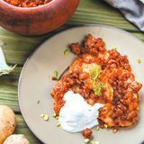 Ukrainische "Rösti" mit Hackfleisch  Zutaten:  · 6–8 Kartoffeln · 200 g Sauerrahm · 2 Zwiebeln · 2 Eier · 4–5 EL Mehl · 150 g Salo (ukrainischer Rückenspeck vom Schwein), Schweinespeck oder fetter Bauchspeck, gewürfelt · 350 g Hackfleisch (am besten frisch durch den Fleischwolf gedreht) · 2 EL Tomatenmark · 5–6 EL Pflanzenöl · Salz, Pfeffer  1 Stunde, 4 Personen  Zubereitung:  1. Den Backofen auf 180 °C vorheizen.  2. Die Kartoffeln auf der groben Seite der Vierkantreibe raspeln. Dann auf der feinen Seite eine der beiden Zwiebeln reiben.  1 EL Sauerrahm, die geriebene Zwiebel sowie Eier, Salz, Pfeffer und Mehl zugeben. Alles gut verrühren und die Masse in einer heißen Pfanne mit Öl von beiden Seiten goldbraun braten.  3. In einer zweiten Pfanne den gewürfelten Speck auslassen und die in kleine Würfel geschnittene zweite Zwiebel darin anbraten. Das Hackfleisch zugeben und anbraten, bis es halbgar ist. Tomatenmark, etwas Wasser sowie Salz und Pfeffer unterrühren und 5 Minuten braten, bis die Flüssigkeit verdunstet ist.  4. Die gebratene Kartoffelmasse und das Hackfleisch auf Portionsschalen aufteilen und jeweils 2 EL Sauerrahm darauf klecksen. Im heißen Ofen 15–20 Minuten backen und mit Sauerrahm als Beilage servieren.