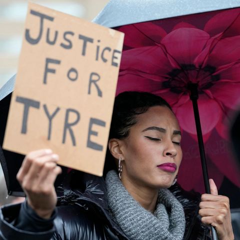 Eine Frau hält ein Schild mit der Aufschrift "Justice for Tyre"