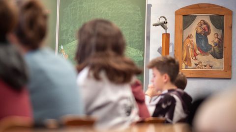 Schüler sitzen in der Freie Waldorfschule Uhlandshöhe vor einem christlichen Bild