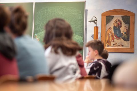 Schüler sitzen in der Freie Waldorfschule Uhlandshöhe vor einem christlichen Bild