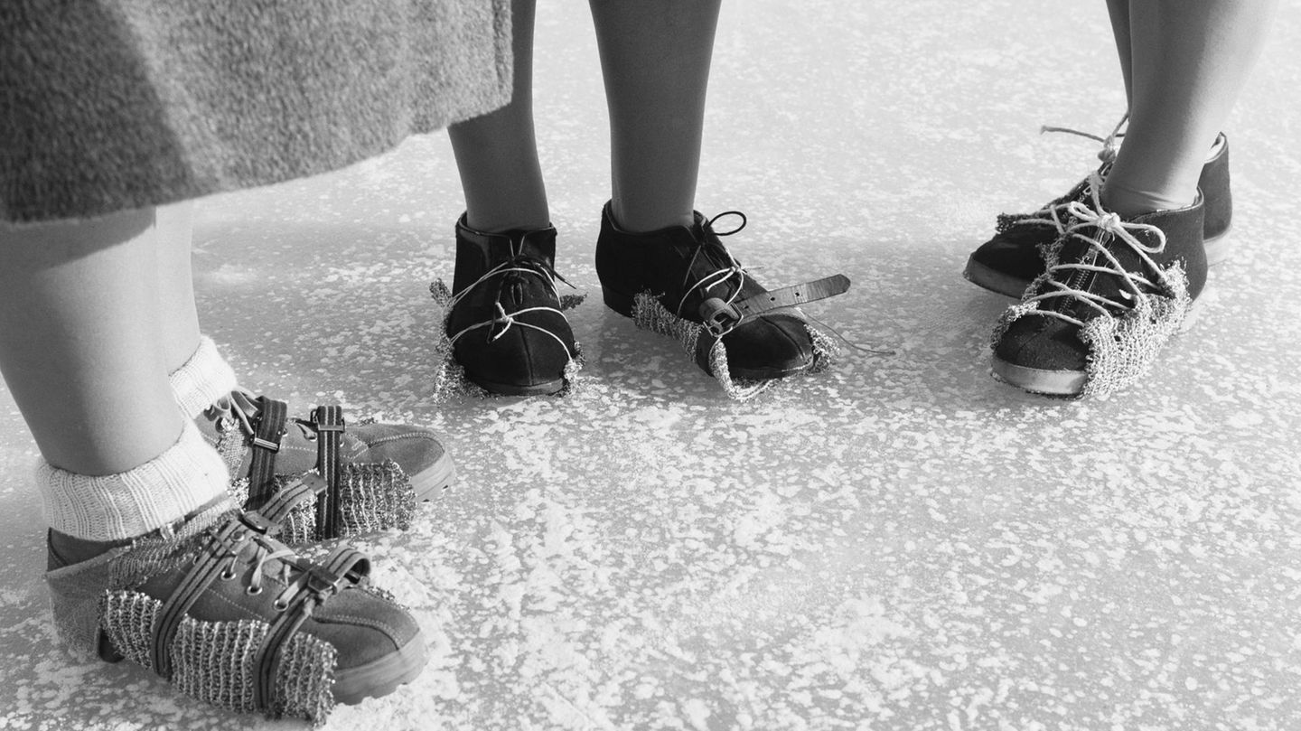 Drei Frauen stehen in Antirutschhilfen unter den Schuhen auf dem zugefrorenen Bodensee