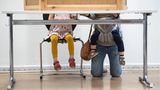 Eine junge Mutter mit zwei Kinder kniet hinter einer Wahlkabine in Berlin