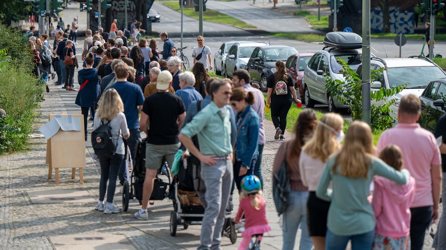 Anstehen Zahlreiche Menschen stehen in einer langen Schlange vor den Wahllokalen