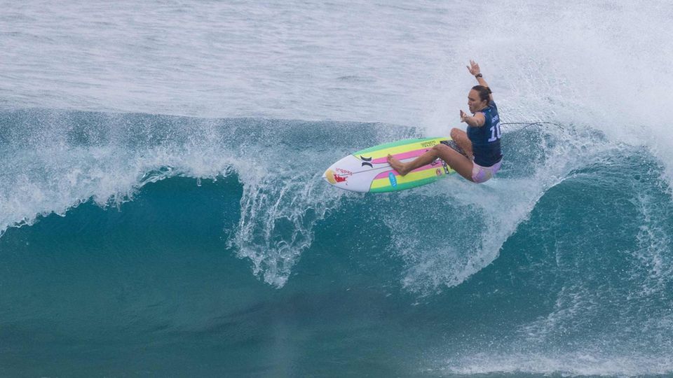 Carissa Moore Billabong Pipeline Pro Hawaii Eine Frau auf einem bunt gestreiften Surfbrett reitet mit ausgebreiteten Armen eine brechende Welle
