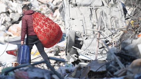 Ein Mann in der Türkei trägt seine Habseligkeiten über Trümmerteile