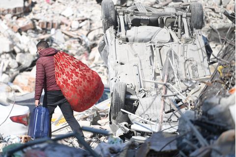 Ein Mann in der Türkei trägt seine Habseligkeiten über Trümmerteile