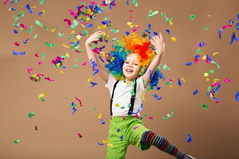 Faschingsspiele für Kinder: Jungs im Clownskostüm spielt mit bunten Papierschnipseln
