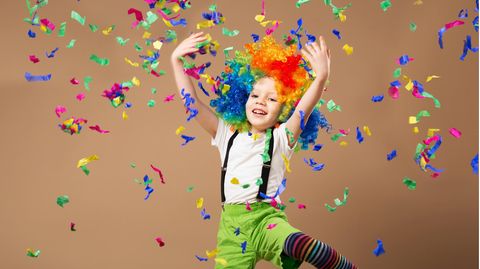Faschingsspiele für Kinder: Jungs im Clownskostüm spielt mit bunten Papierschnipseln