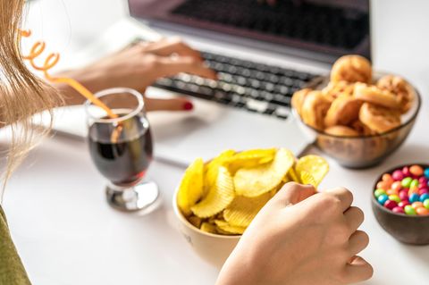 Frau isst Cola, Chips und Süßes