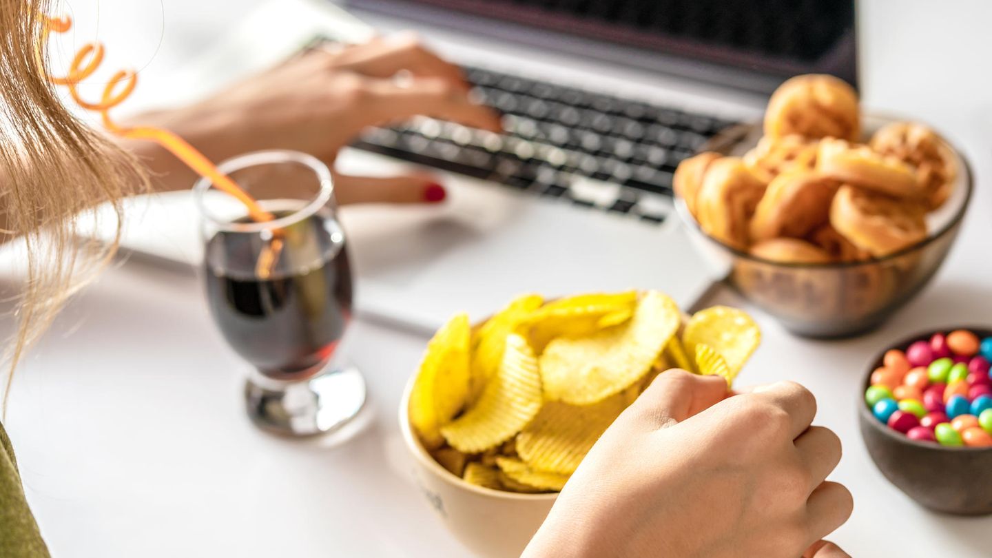 Frau isst Cola, Chips und Süßes