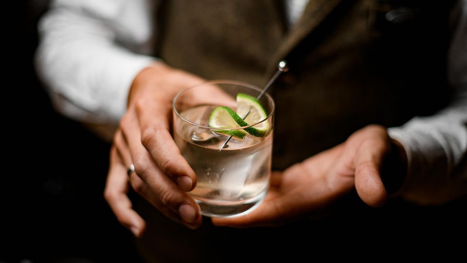 Barkeeper hält einen Gin Tonic in der Hand