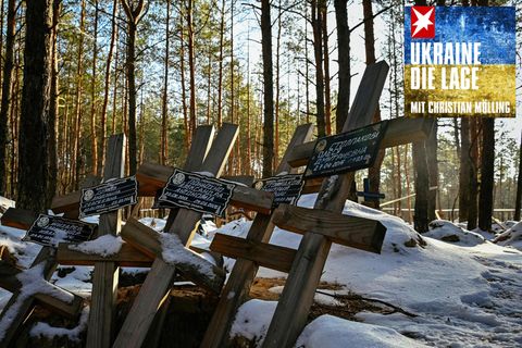 Grabkreuze liegen in einem verschneiten Wald bei Sonnenschein