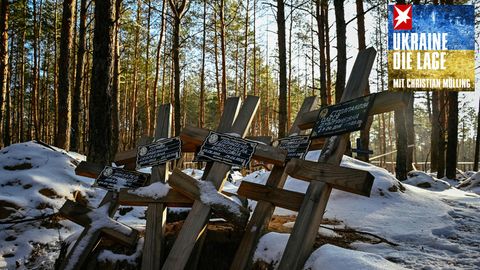 Grabkreuze liegen in einem verschneiten Wald bei Sonnenschein