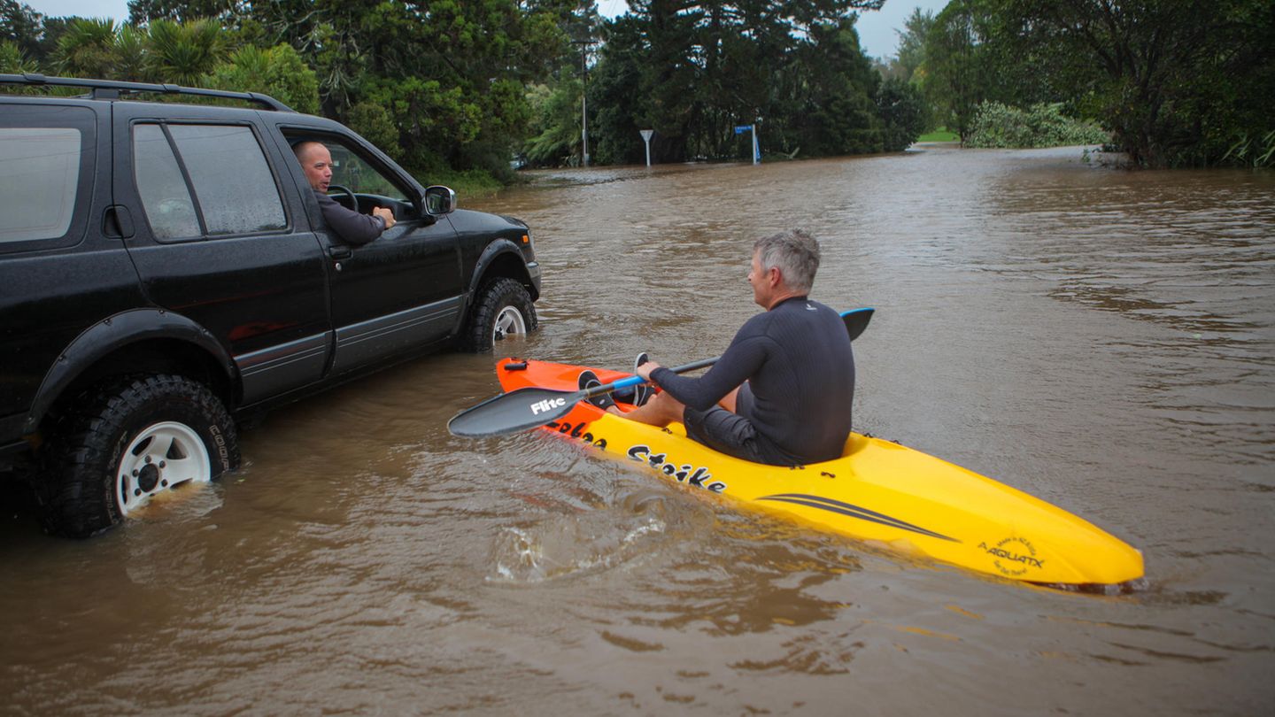 Ein Mann fährt im Kajak über eine überflutete Straße in Auckland